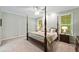 Light-filled bedroom features a four-poster bed, neutral carpet, and windows with wooded views at 501 Avery Creek Pointe, Woodstock, GA 30188