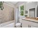 Bright bathroom with a shower-tub combination, granite counters, and large window at 115 Greenbrier Way, Canton, GA 30114