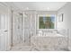 Bright bathroom features a large soaking tub, a glass enclosed shower and marble-look tile at 115 Greenbrier Way, Canton, GA 30114