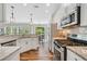 Open kitchen boasts stainless appliances, light granite counters, and hardwood floors with eat-in area at 115 Greenbrier Way, Canton, GA 30114