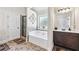 Bright bathroom with white tub, glass shower, and stylish dark wood vanity at 3024 Bridgehaven Ct, Snellville, GA 30039