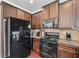 Well-equipped kitchen with black appliances, granite countertops, and dark wood cabinets at 3024 Bridgehaven Ct, Snellville, GA 30039