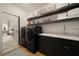 Modern laundry room featuring dark cabinets, floating shelves, a marble countertop, and dark, front-loading machines at 633 Channing Nw Dr, Atlanta, GA 30318