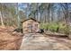 Wood shed with double doors and a concrete driveway in a wooded backyard at 5642 N Highway 212, Covington, GA 30016