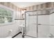 Traditional bathroom with glass shower doors, white tile, and a pedestal sink by a bright window at 22 Peachtree Hills Ne Ave, Atlanta, GA 30305