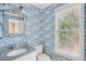 Cozy bathroom with blue wallpaper, white vanity, and window offering natural light and tree views at 22 Peachtree Hills Ne Ave, Atlanta, GA 30305