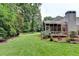 Large grassy backyard with mature trees, screened-in porch, and landscaped garden beds at 9585 Fenbrook Ct, Johns Creek, GA 30022