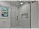 Modern bathroom shower featuring elegant marble tile surround, a window, and shelf storage at 9585 Fenbrook Ct, Johns Creek, GA 30022