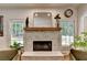 Cozy living room features a stone fireplace, wood mantel, and decorative plants at 9585 Fenbrook Ct, Johns Creek, GA 30022