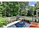 Outdoor patio with seating, grill, and potted plants, surrounded by lush greenery and trees at 9585 Fenbrook Ct, Johns Creek, GA 30022