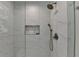 Modern bathroom shower featuring elegant marble tile surround and recessed shelf at 9585 Fenbrook Ct, Johns Creek, GA 30022