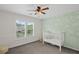 Bedroom showcases a cute mural wall, window with white shutters, neutral carpet, and a baby bed at 640 Windwalk Dr, Roswell, GA 30076