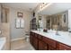 Bathroom featuring double sink vanity, framed mirrors, tiled floors and walls, and glass-enclosed shower at 442 Colonial Walk, Woodstock, GA 30189