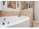 Bright bathroom featuring tiled walls, soaking tub, and separate tiled glass-enclosed shower at 442 Colonial Walk, Woodstock, GA 30189