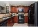A functional kitchen boasts dark granite counters, wood cabinets, and modern black appliances at 442 Colonial Walk, Woodstock, GA 30189