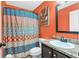 Vibrant bathroom featuring a patterned shower curtain, vanity with sink, and an orange accent wall at 218 Depot Ln, Dallas, GA 30157