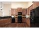 Well-equipped kitchen with dark granite countertops, wood cabinets, and black appliances at 328 Brookhaven Walk, Johns Creek, GA 30097