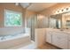 Bright bathroom with white cabinets, a tiled tub and separate glass enclosed shower at 3750 Cannonwolde Dr, Snellville, GA 30039