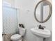 Well-lit bathroom with pedestal sink, commode, and patterned shower curtain at 6175 Beaver Crossing Dr, Cumming, GA 30040