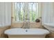 Elegant bathroom featuring a clawfoot tub, pedestal sink, bright window and stylish decor at 1850 Winchester Trl, Brookhaven, GA 30341
