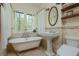 Charming bathroom with clawfoot tub, pedestal sink, decorative tile and bright windows showcasing a wooded view at 1850 Winchester Trl, Brookhaven, GA 30341