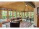 Bright sunroom with wood ceiling, large windows with views of wooded landscape, and comfortable seating arrangement at 1850 Winchester Trl, Brookhaven, GA 30341