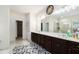 Bright primary bathroom with dual sinks, dark cabinets, a large mirror, and walk-in closet at 610 Brickstone Ct, Covington, GA 30016