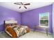 Cozy bedroom featuring lavender-painted walls, queen bed, ceiling fan, and natural light at 610 Brickstone Ct, Covington, GA 30016