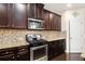 Updated kitchen featuring stainless steel appliances, dark cabinetry, and tile backsplash at 610 Brickstone Ct, Covington, GA 30016
