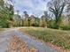 Scenic view of a gravel driveway leading to a property, surrounded by trees with fall foliage and lush green grass at 2760 Hembree Ne Rd, Marietta, GA 30062