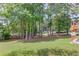 Grassy backyard with mature trees and a partial view of a wooden deck at 3082 Biltmore Woods Dr, Buford, GA 30519