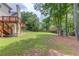 Large, grassy backyard with mature trees and a wooden fence in the background at 3082 Biltmore Woods Dr, Buford, GA 30519