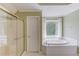 Bathroom featuring a soaking tub next to a window and glass shower doors at 3082 Biltmore Woods Dr, Buford, GA 30519