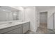 Modern bathroom featuring double sinks, neutral cabinetry, and an open doorway to the closet at 8593 Secretariat Drive, Lithonia, GA 30058