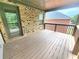 Covered wooden deck featuring brick accents and wood railing with views of the backyard and greenery at 827 Autry Oak Ct, Johns Creek, GA 30022