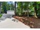 Long concrete driveway leads to a beautiful home with a three-car garage surrounded by trees at 1824 Mount Paran Nw Rd, Atlanta, GA 30327