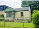 A single-story home with green trim is surrounded by a chain-link fence and overgrown yard at 133 Buchanan Ln, Atlanta, GA 30315