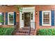 Close-up of a red brick home's front entrance with black shutters and a storm door at 4313 Deep Springs Nw Ct, Kennesaw, GA 30144