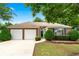 Charming brick home with a manicured front yard, lush green bushes, and a two-car garage at 910 Laurel Cove Dr, Snellville, GA 30078