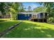 Backyard featuring a lush lawn, stone accents, and a bright blue house with a wooden deck at 2011 Lexington Ave, Atlanta, GA 30344