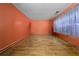 Empty room with orange walls, hardwood floors, and a window letting in natural light at 8320 Mayfern Dr, Fairburn, GA 30213