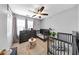 Neutral toned bedroom with two cribs, a ceiling fan, and a triple window for lots of natural light at 8320 Mayfern Dr, Fairburn, GA 30213