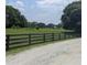 Beautiful countryside land with a wooden fence, trees, and grassy areas, perfect for outdoor activities at 10540 Serenbe Ln, Chattahoochee Hills, GA 30268