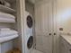 Bathroom area features a stacked washer/dryer and shelving for ample storage at 10540 Serenbe Ln, Chattahoochee Hills, GA 30268