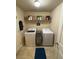 Laundry room features modern washer, dryer, wire shelving, and tile flooring at 124 Gorham Gates Ct, Hiram, GA 30141