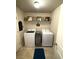 Well-organized laundry room with a front-loading washer and dryer, storage shelf, and tiled floors at 124 Gorham Gates Ct, Hiram, GA 30141