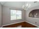 Neutral dining area featuring a chandelier, large window, hardwood flooring, and an arched doorway at 5414 Sweetsprings Sw Dr, Powder Springs, GA 30127