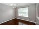 Elegant dining area features hardwood floors, a chandelier, neutral walls, and a large window with blinds at 5414 Sweetsprings Sw Dr, Powder Springs, GA 30127