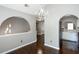 Elegant dining area with dark wood floors, a chandelier, and arched doorways leading to the entryway and kitchen at 5414 Sweetsprings Sw Dr, Powder Springs, GA 30127