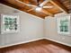 Inviting bedroom featuring wood floors, wood-beamed ceilings with fan, and bright natural light from large windows at 5642 Dorsett Shoals Rd, Douglasville, GA 30135